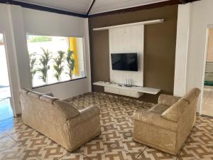 a living room with two chairs and a flat screen tv at Rancho condominio Lago e Sol - com piscina aquecida e ar condicionado in Fronteira
