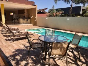 a patio with a table and chairs next to a swimming pool at Rancho condominio Lago e Sol - com piscina aquecida e ar condicionado in Fronteira