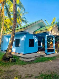 ein blaues Haus mit einer Palme davor in der Unterkunft Colorful Tropical Bungalow in Bacong