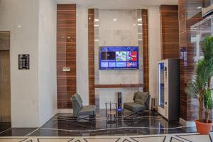 a lobby with chairs and a tv on the wall at Indigo Apartments in Jeddah