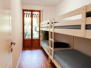 Una habitación con dos literas y una puerta. en MareBlu Apartment with patio, en Marina di Castagneto Carducci