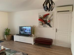 a living room with a tv on a white cabinet at Charmant 3 pièces vue mer in Antibes