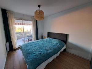 a bedroom with a bed with a green comforter and a window at Charmant 3 pièces vue mer in Antibes