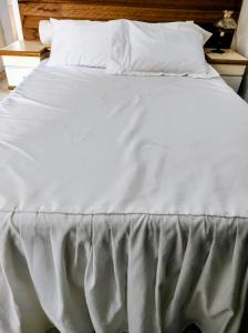 un letto con lenzuola bianche e cuscini sopra di Mi Casa Rio Garagem Wi-Fi Grátis Próximo Praia Barra a Rio de Janeiro