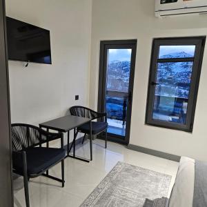 a living room with a table and chairs and windows at Panorama Lux Guest House in Chimgan
