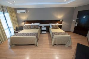 プエルトイグアスにあるBagu ÑAMANDU GUAZUのベッド2台とテーブルがあるホテルの部屋