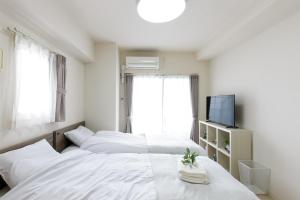 a white bedroom with two beds and a television at KOMOREBI SQUARE Osu in Nagoya