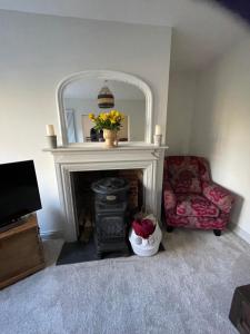 a living room with a fireplace and a chair and a mirror at Chestnut Cottage in Great Ellingham