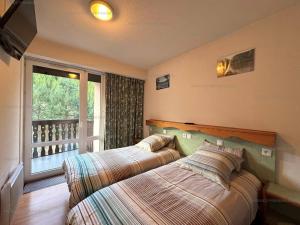 two beds in a bedroom with a balcony at Appart 6 pers aux pieds des pistes avec balcon, wifi, parking - FR-1-295-183 in Les Angles