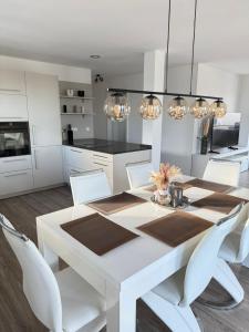 a white dining room with a white table and chairs at Penthousewohnung zum Wohlfühlen in Weyhausen
