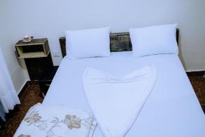 a bed with white sheets and pillows in a room at BC Empire Luxury Guest House in Kigali