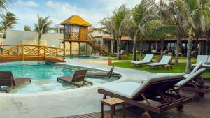 a resort pool with chairs and a gazebo at Carnaúba Hotel Boutique in Aquiraz