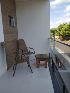 a balcony with two chairs and a coffee table at Casa Amarte - Sobrado Privado com Garagem in Guaíra