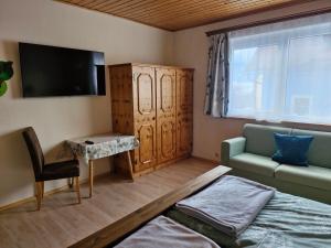 pokój z łóżkiem, telewizorem i kanapą w obiekcie Ferienwohnung Hohengaßner w mieście Mariapfarr