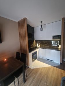 a kitchen with white cabinets and a wooden table at Apartament Spokojny Czas in Wisła