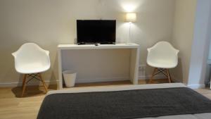 バルセロナにあるオスタル エル ニノートのベッドルーム1室(白い椅子2脚、薄型テレビ付)
