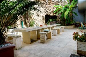 a table and benches in a courtyard with plants at Residence Atenaion in Otranto +21 photos