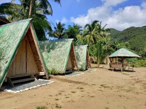 a group of huts on a beach with palm trees at Camp Irog Daraitan in Damasanan +42 photos