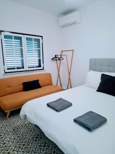 ein Schlafzimmer mit einem weißen Bett und einer Couch in der Unterkunft Casa da Paz #1 in Vila Nova de Milfontes
