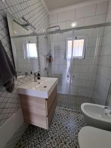 ein weißes Badezimmer mit Waschbecken und Dusche in der Unterkunft Casa da Paz #1 in Vila Nova de Milfontes + 7 Fotos