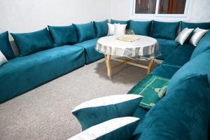 a blue couch in a living room with a table at Hogar Feliz - apartment in Agadir