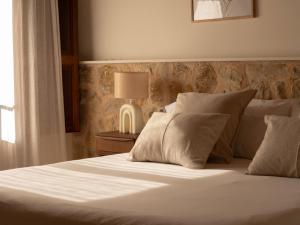 a bed with white sheets and pillows next to a lamp at Es Petit de Valldemossa in Valldemossa