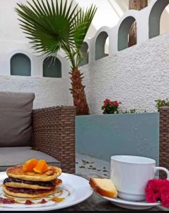 un tavolo con un piatto di pancake e una tazza di caffè di Lefkothea Hotel a Kamari