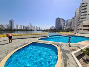 a man and a child standing next to a swimming pool at Laguito Apartment in Cartagena de Indias