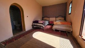 a room with three beds and a mirror in it at Mhamid camp happy night in Mhamid