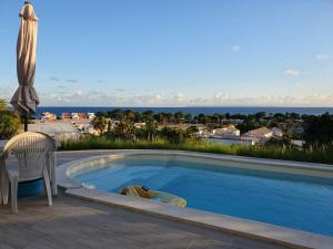 a swimming pool with a chair and an umbrella at La Zénitude 2 haut de villa Vues exceptionnelles in Saint-François