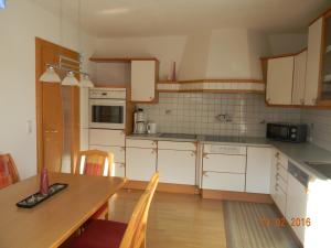 ヴェンスにあるFerienwohnung Gasserのキッチン(白いキャビネット、木製テーブル、椅子付)