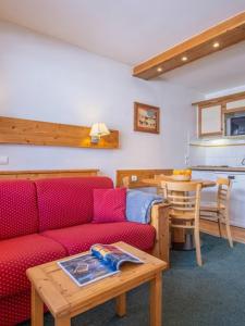 a living room with a red couch and a table at Citea Meribel Peillon Pierre et Vacances in Méribel