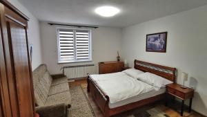 a bedroom with a bed and a chair and a window at Penzión u Marlenky in Spišská Stará Ves