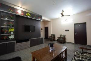 a living room with a table and a tv at Goutham Residency in Vadalūr