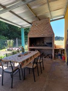 eine Terrasse mit einem Tisch, Stühlen und einem Kamin in der Unterkunft Campos del Paraná Casa Quinta in San Pedro