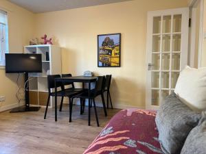 un salon avec une table, des chaises et une télévision dans l'établissement One room with parking space, à Édimbourg