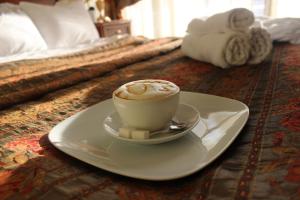 a cup of coffee on a plate on a bed at Hotel Lux Angliter in Vologda