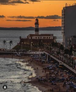 a beach with a lighthouse and a crowd of people at Apartment in Ondina, Carnival Circuit, Luxury in Salvador