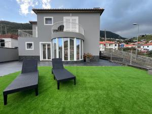 een huis met twee stoelen op een groen gazon bij Villa Machico Valley Flat 2 in Machico