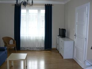 ein Wohnzimmer mit einem TV und einem Fenster in der Unterkunft Apartmán U krále Tylova 516 in Jičín