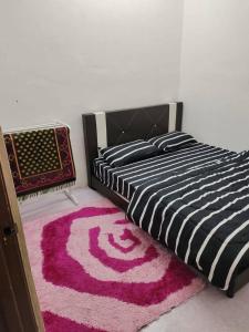 a bedroom with a black and white bed with a pink rug at Homestay Kota Bharu in Kota Bharu