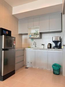a kitchen with white cabinets and a stainless steel refrigerator at SURIA HomeStay Kuala Terengganu City Center, 8 pax, 150M to KTCC Mall in Kuala Terengganu