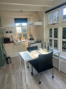 a kitchen with a white table and chairs and windows at Appartement de Tuinkamer in Ter Apel