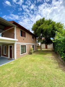 a house with a tree and a grass yard at Cabaña en el Centro de Mina Clavero in Mina Clavero