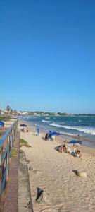 una playa con gente tirada en la arena y sombrillas en Quarto em residência - Piatã, en Salvador