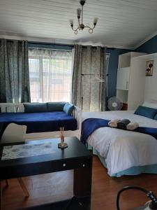 a bedroom with two beds and a couch and a table at Stay at Gabby's- no loadshedding in Cape Town