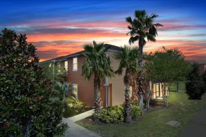 a house with palm trees in front of a sunset at Three Bedrooms Townhome 3012 in Kissimmee