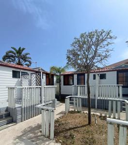 a house with a white fence and a tree at Campeggio Praia Mare in Campofelice di Roccella