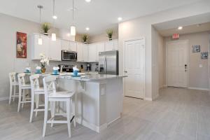 a kitchen with white cabinets and a table and chairs at Four Bedroom w/ GameRoom 5152A in Kissimmee