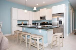 eine Küche mit weißen Schränken und einer Theke mit Stühlen in der Unterkunft Marvelous 4 Bedroom w/ Pool @ Festival Resort 197 in Davenport